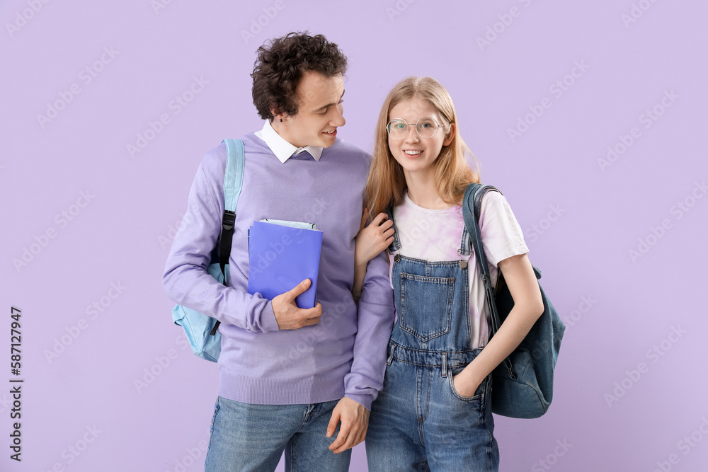 Teenage couple with books on lilac background