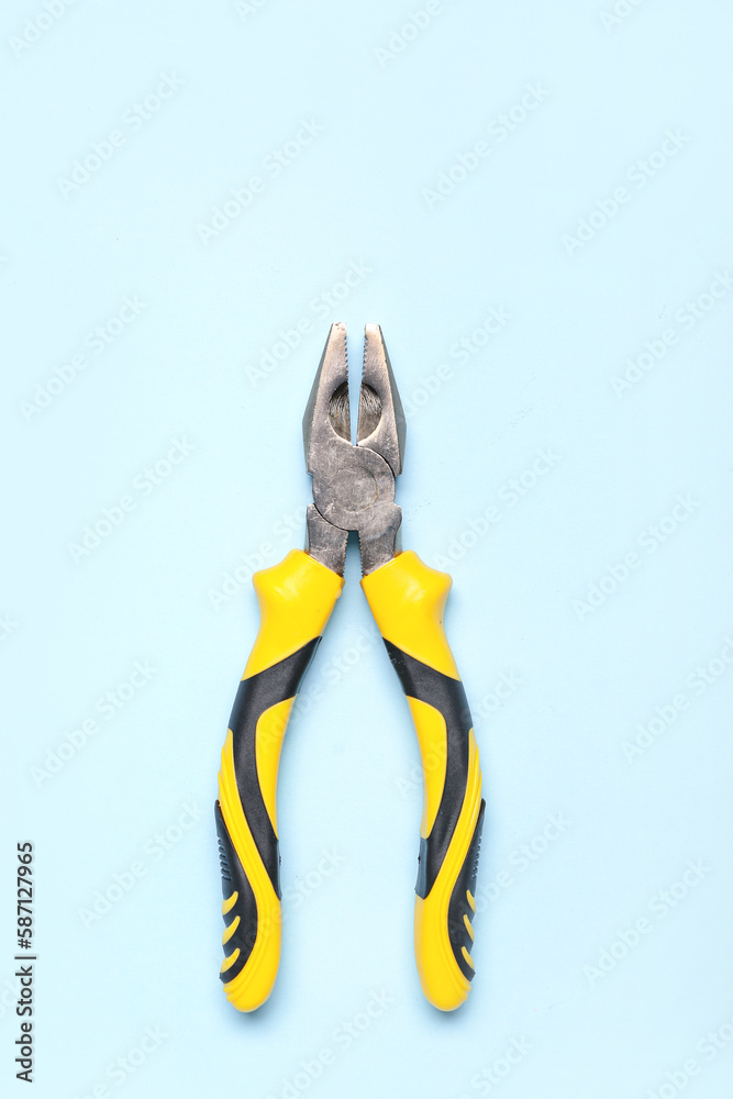 Yellow pliers on blue background