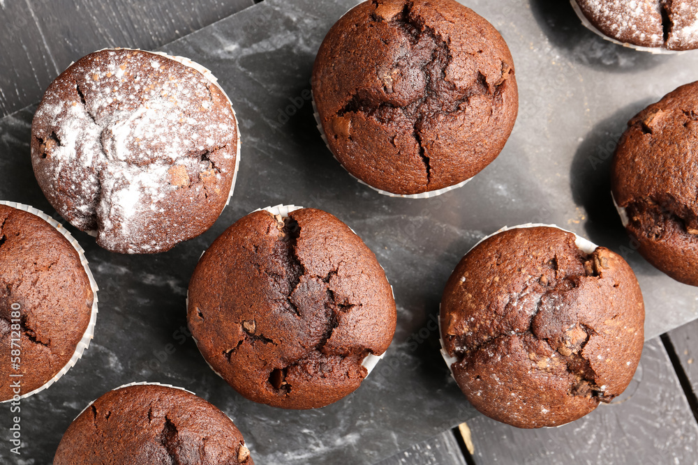 Board with tasty chocolate cupcakes on dark wooden background