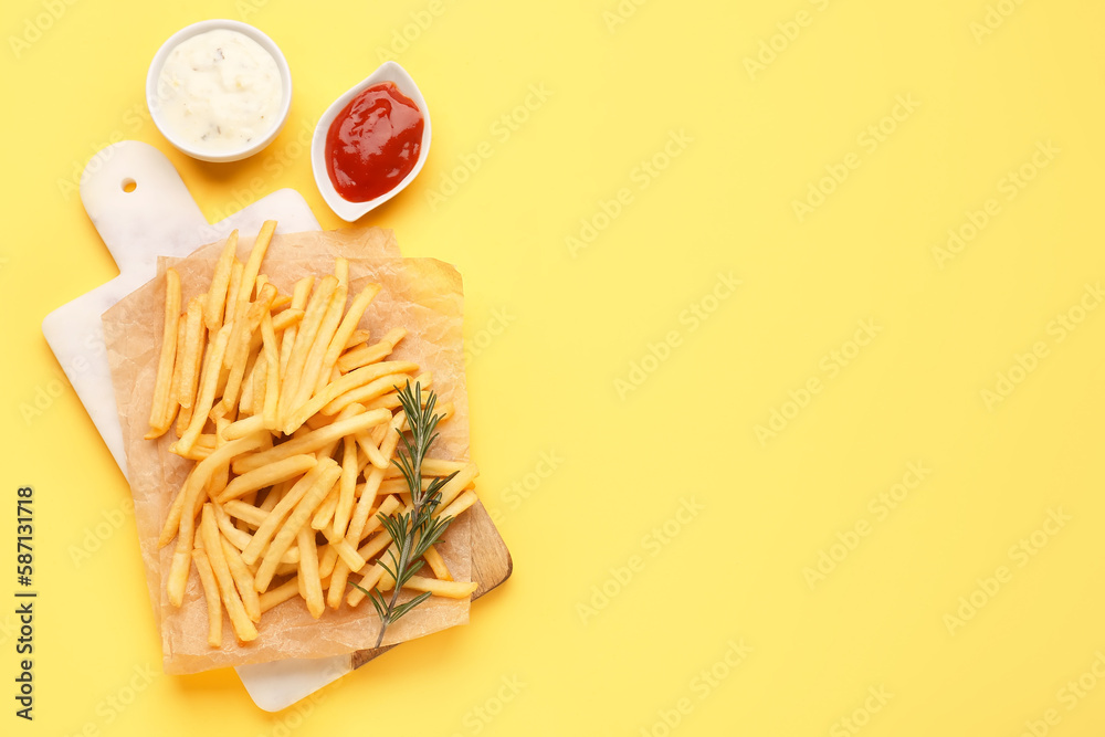 Board with tasty french fries, mayonnaise and ketchup on yellow background