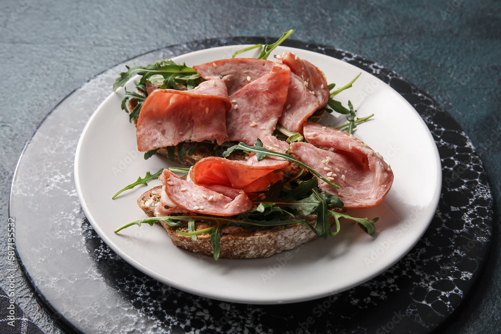 Plate of tasty bruschettas with ham on black background