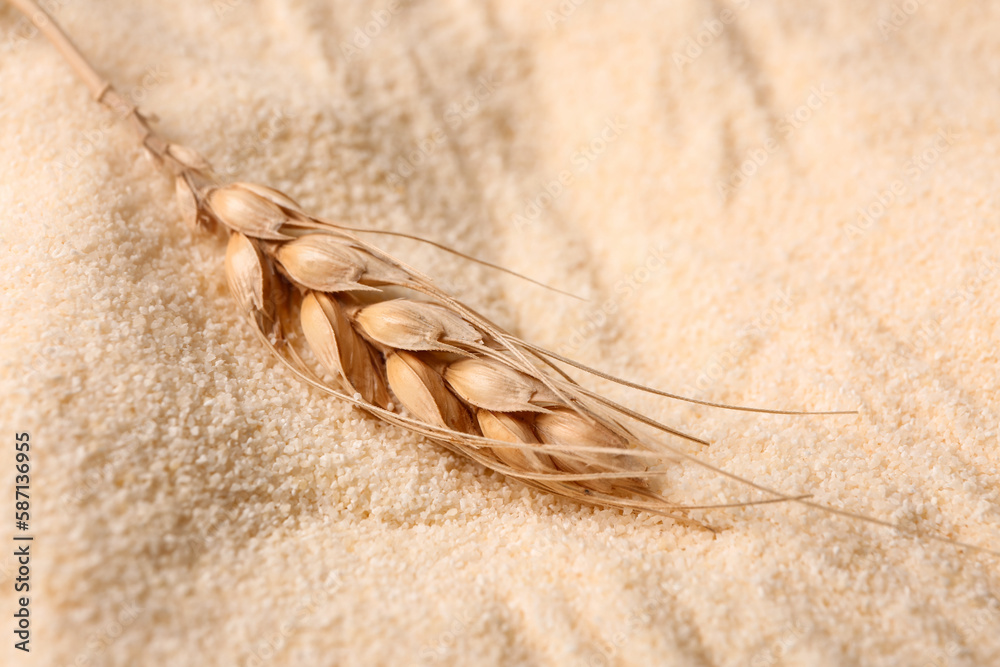 Spikelet with raw semolina as background, closeup