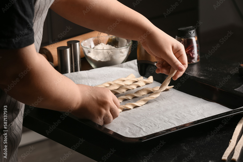 Woman preparing Italian Grissini at table in kitchen, closeup