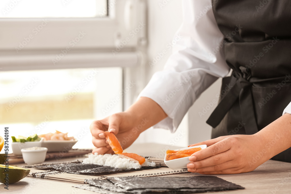 Woman preparing sushi rolls at table, closeup