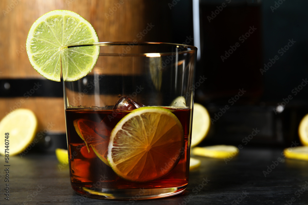 Glass of cold rum with lime on dark background