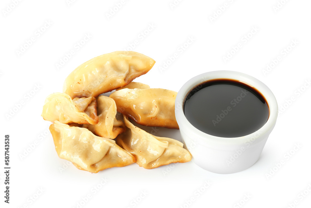 Tasty Chinese jiaozi and bowl of sauce on white background