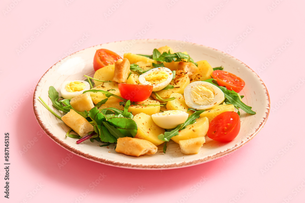 Plate of tasty potato salad with eggs and tomatoes on pink background