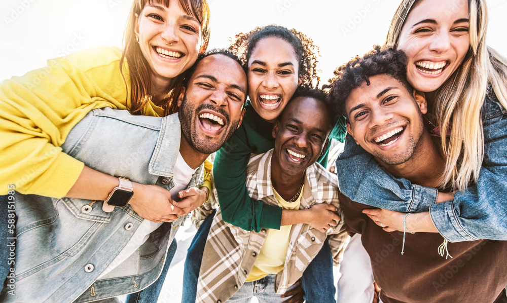 Multiracial young people smiling at camera outside - Group of best friends having fun hanging out to