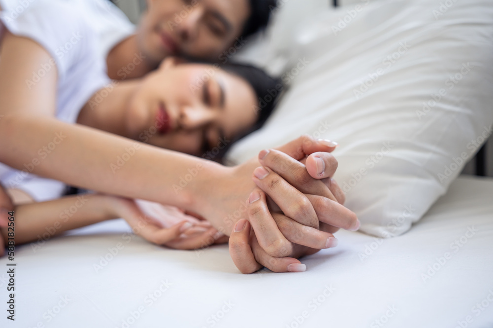 Asian attractive young couple lying down on bed to sleep in bedroom. 