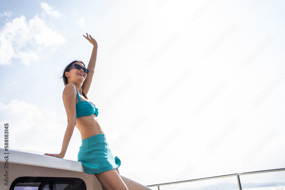 Asian woman wearing bikini looking at beautiful view during yachting