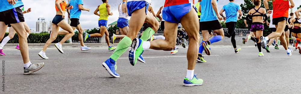 close-up legs runners, men and women, running marathon. athletes jogging city race, summer world cha