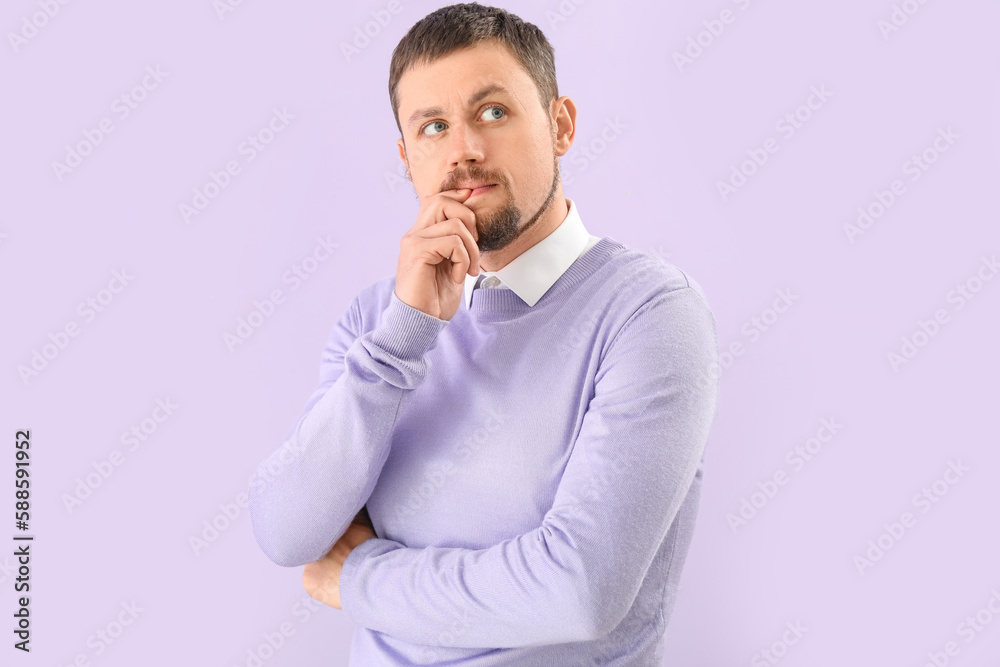 Handsome man biting nails on lilac background