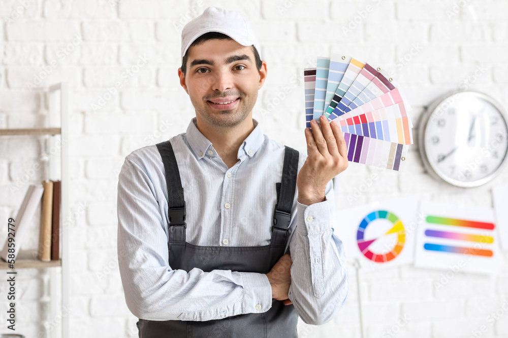 Male painter with color palettes near white brick wall