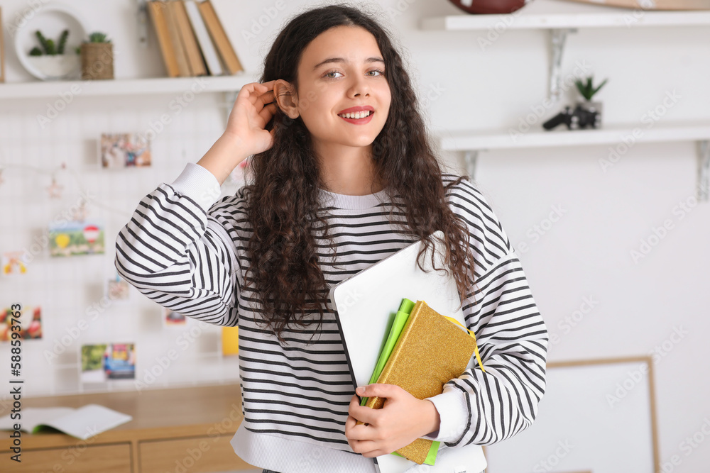 Female student with notebooks and laptop at home