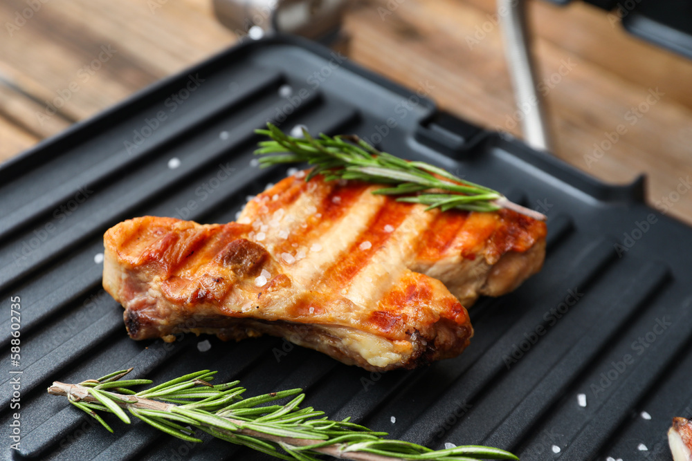 Delicious steaks and rosemary on modern electric grill, closeup