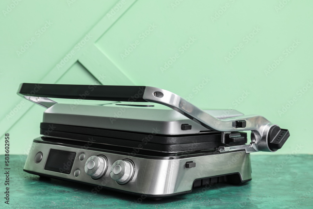 Modern electric grill with closed lid on green table