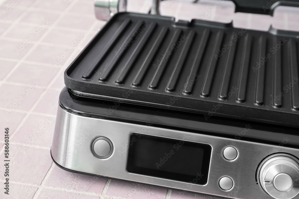 Control panel of modern electric grill on pink tile table, closeup