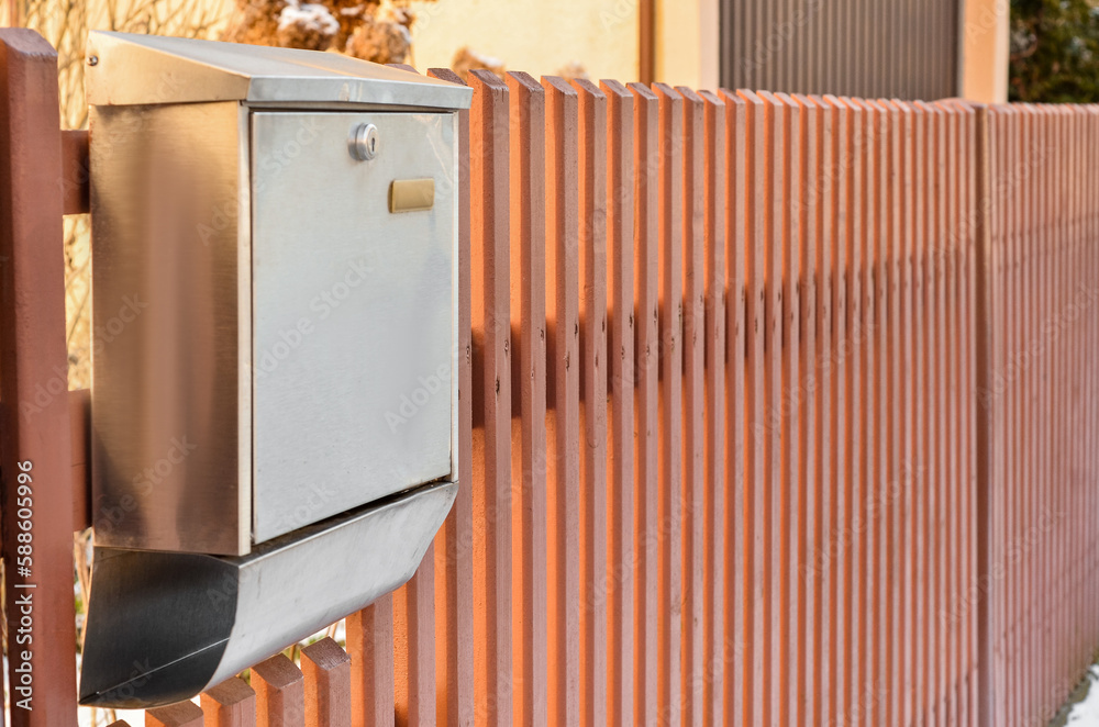 View of metal mailbox on wooden fence, closeup