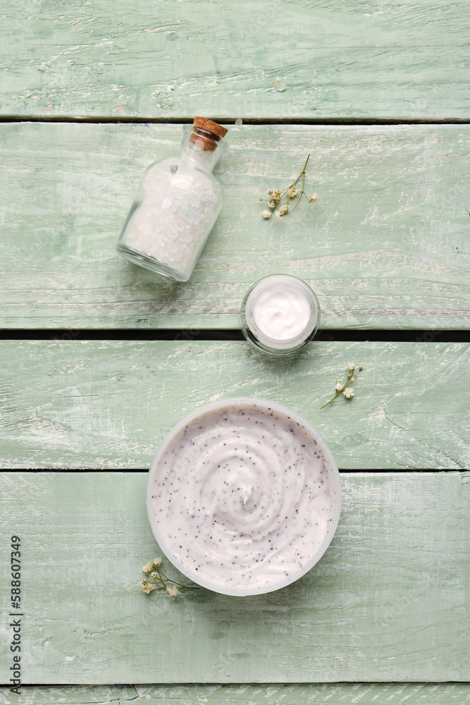 Composition with jar of body scrub, cream and sea salt on color wooden background