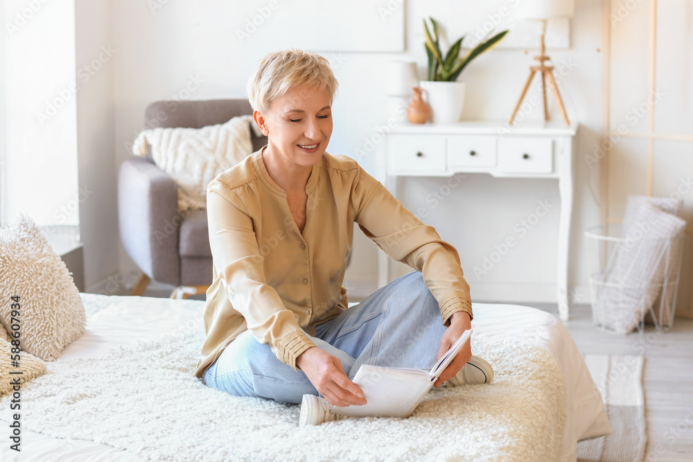 Mature woman reading book in bedroom