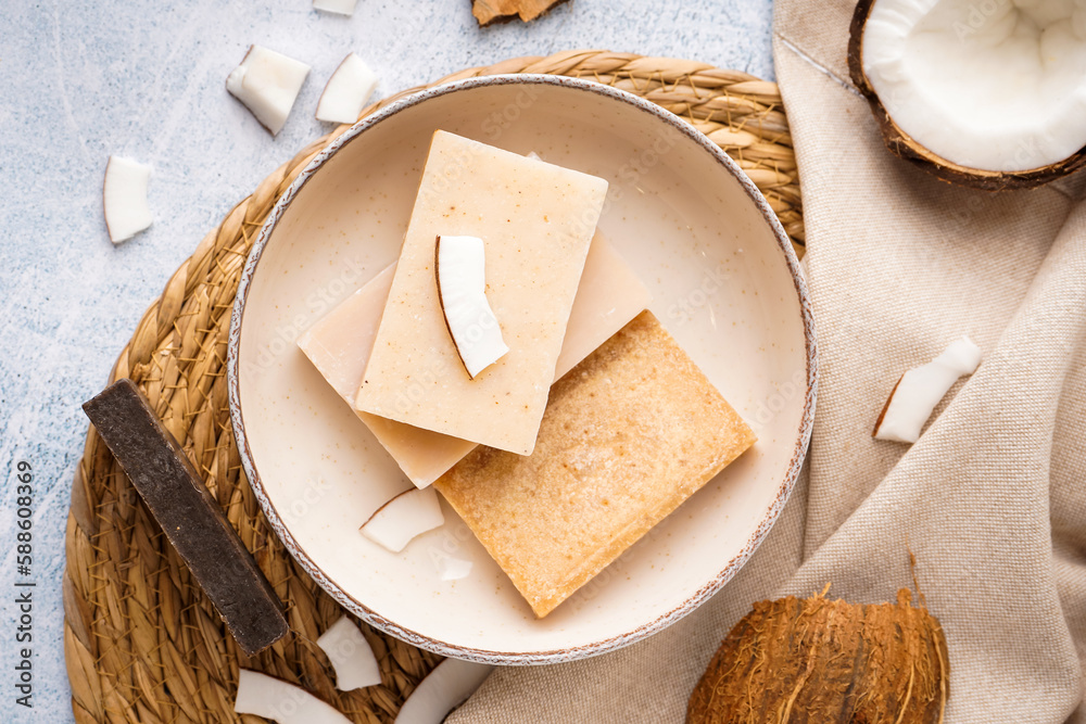 Composition with plate of natural soap bars and coconut on light background, closeup