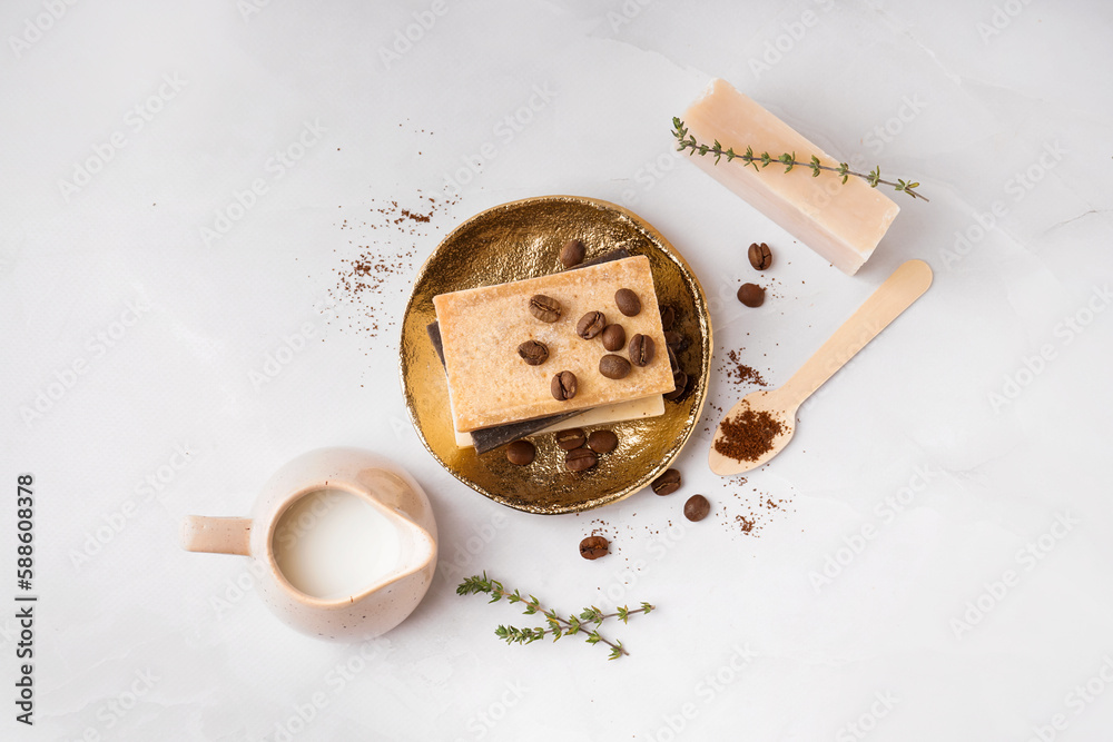 Plate with natural soap bars, coffee beans and milk on light background