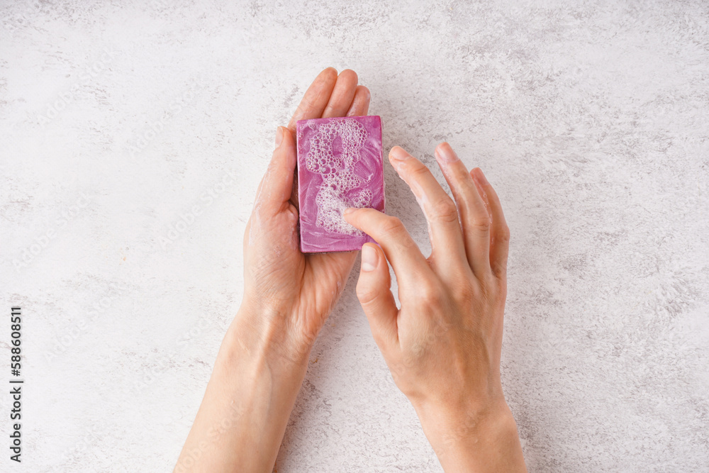 Female hands with natural soap bar on light background, closeup