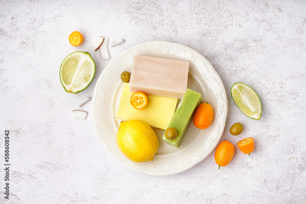 Plate with natural soap bars fruits and olives on light background