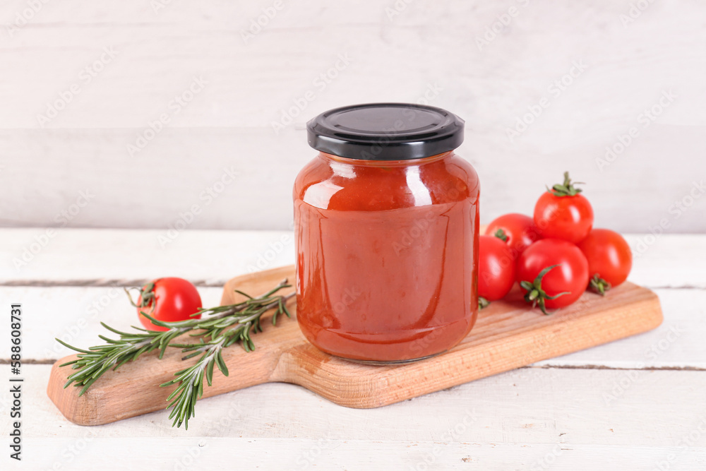 Board with jar of tasty tomato paste on white wooden background