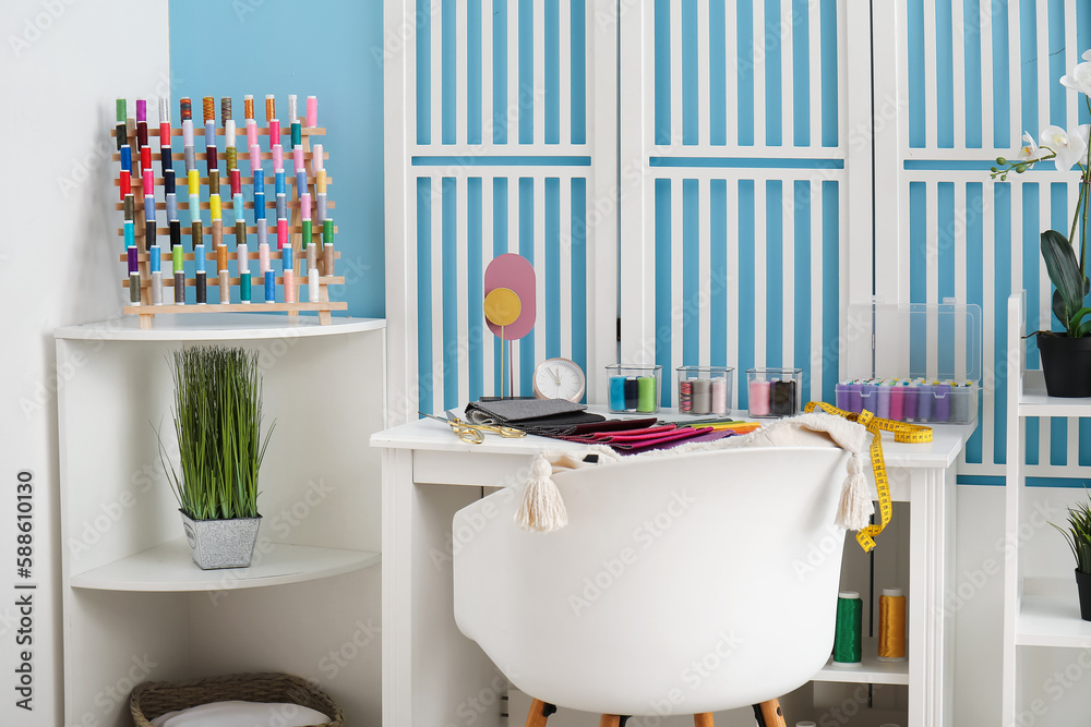 Interior of atelier with tailors workplace, thread spools and shelving unit