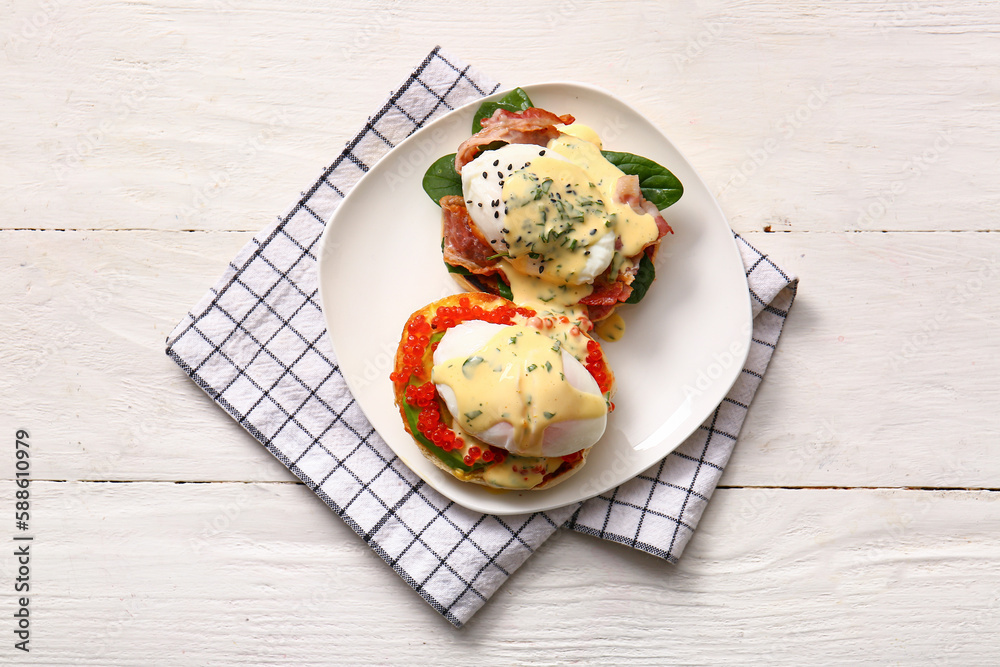 Plate with tasty eggs Benedict on white wooden table