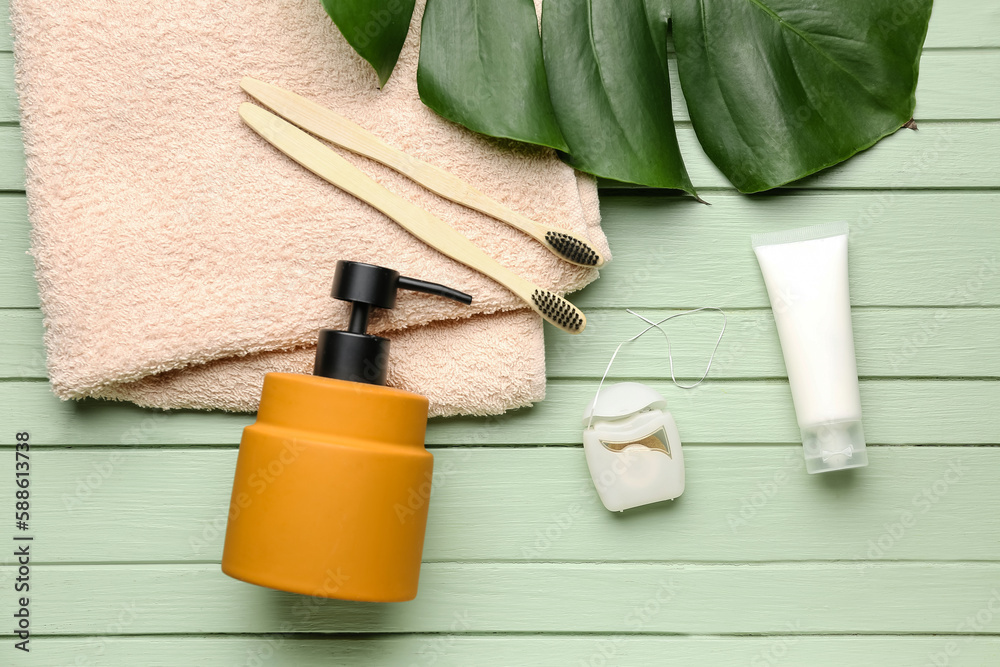 Dental floss and bath accessories on green wooden background