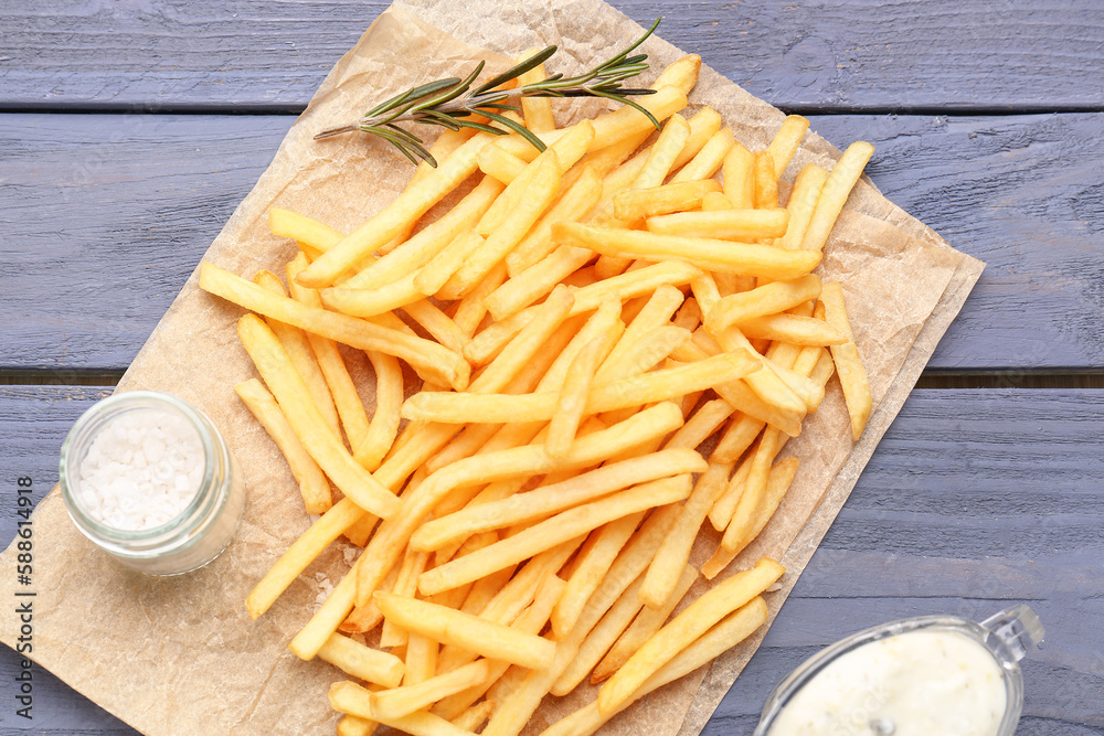 Tasty french fries, salt and mayonnaise on blue wooden background