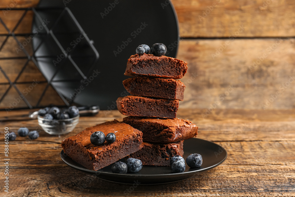 Plate with pieces of tasty chocolate brownie on wooden background