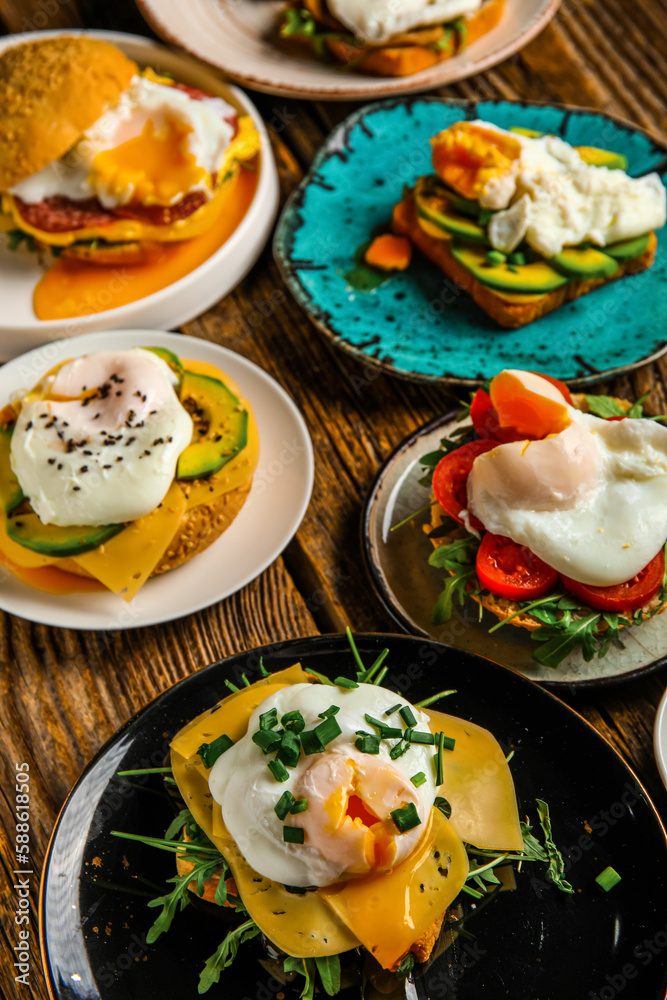 Plates with tasty eggs Benedict on wooden background