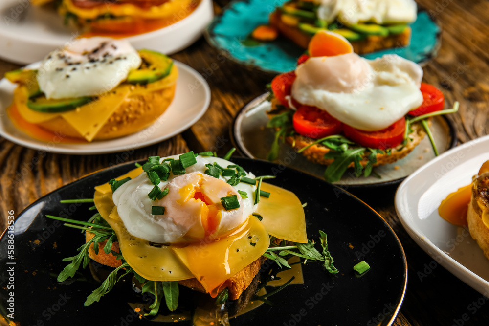 Plates with tasty eggs Benedict on wooden background