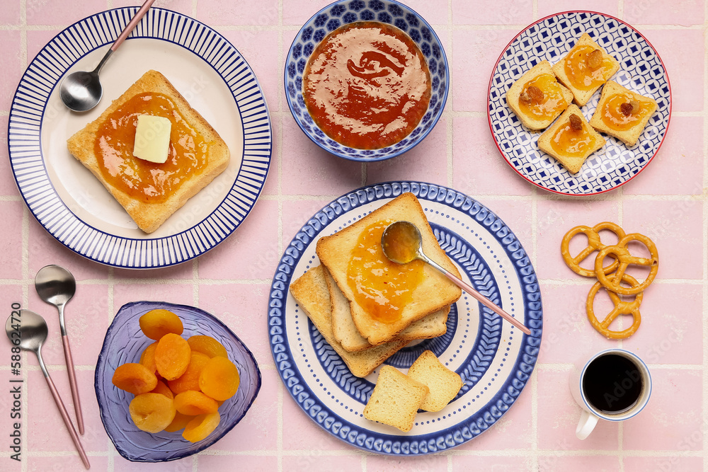 Plates with tasty toasts, apricot jam and cup of coffee on pink tile background