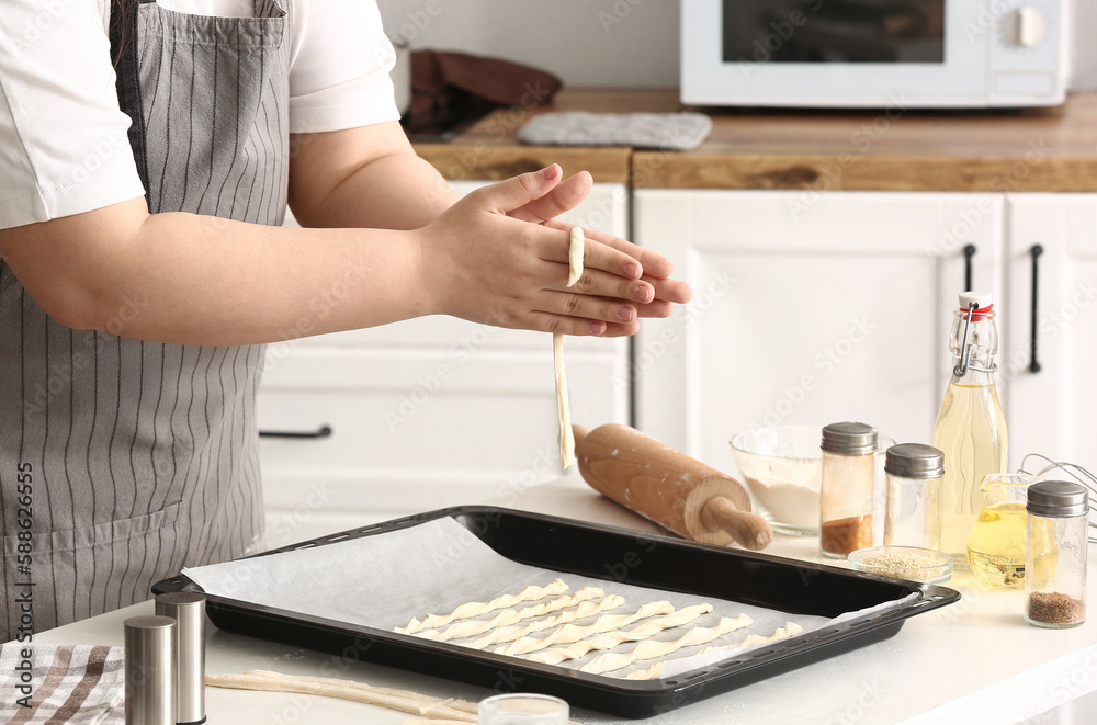 Woman preparing Italian Grissini at table in kitchen, closeup