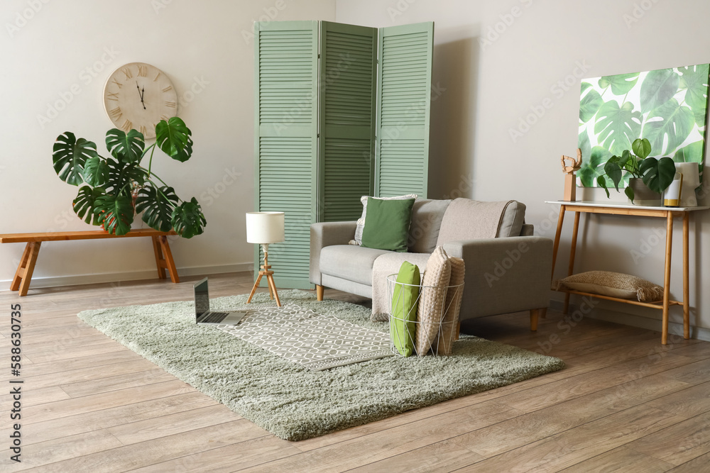 Interior of living room with grey sofa and green folding screen