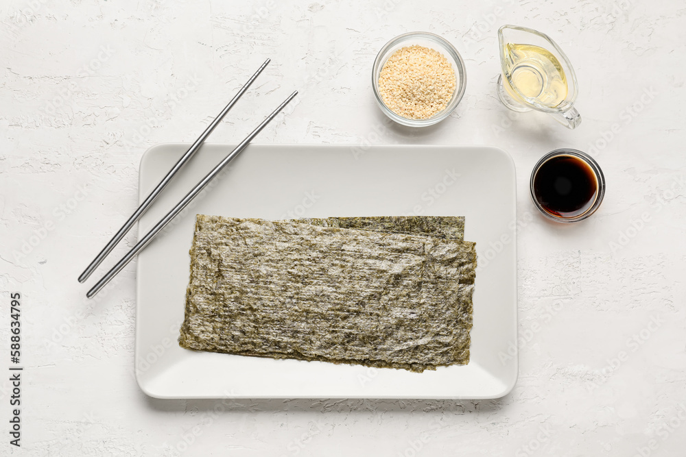 Plate with nori sheets, soy sauce, sesame seeds and vinegar on light background