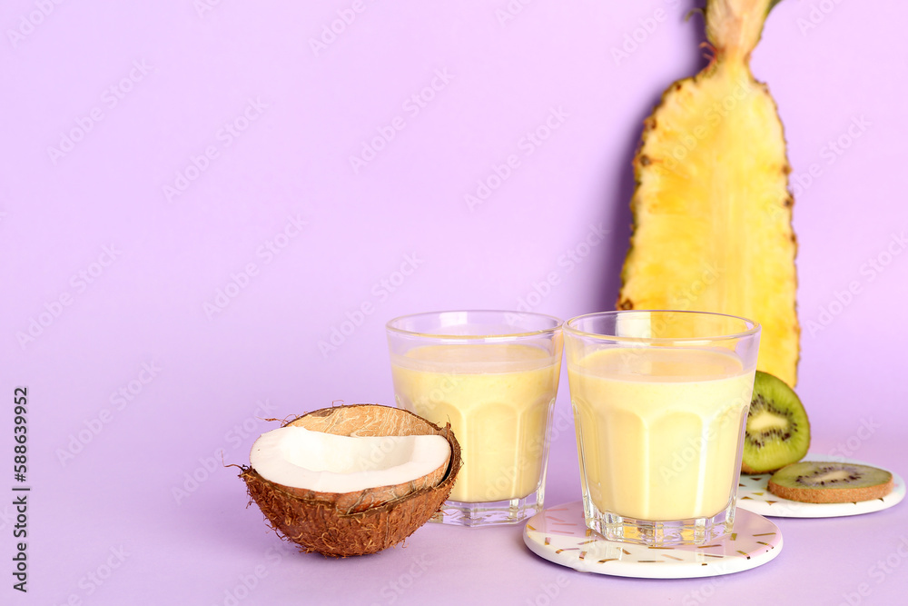 Glass of tasty pineapple smoothie, kiwi and coconut on lilac background