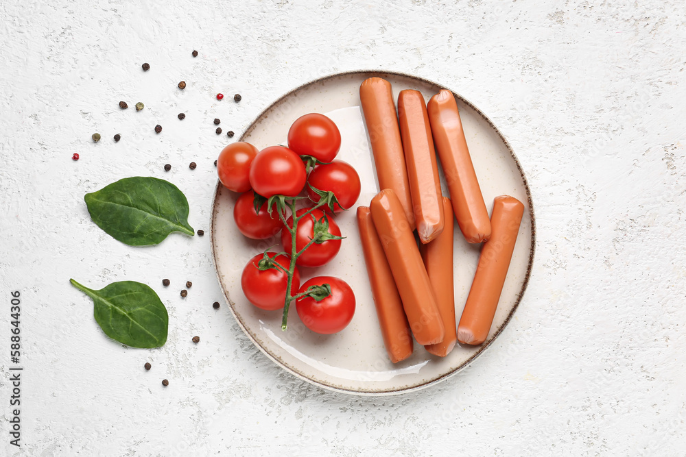 Plate with tasty sausages and tomatoes on light background