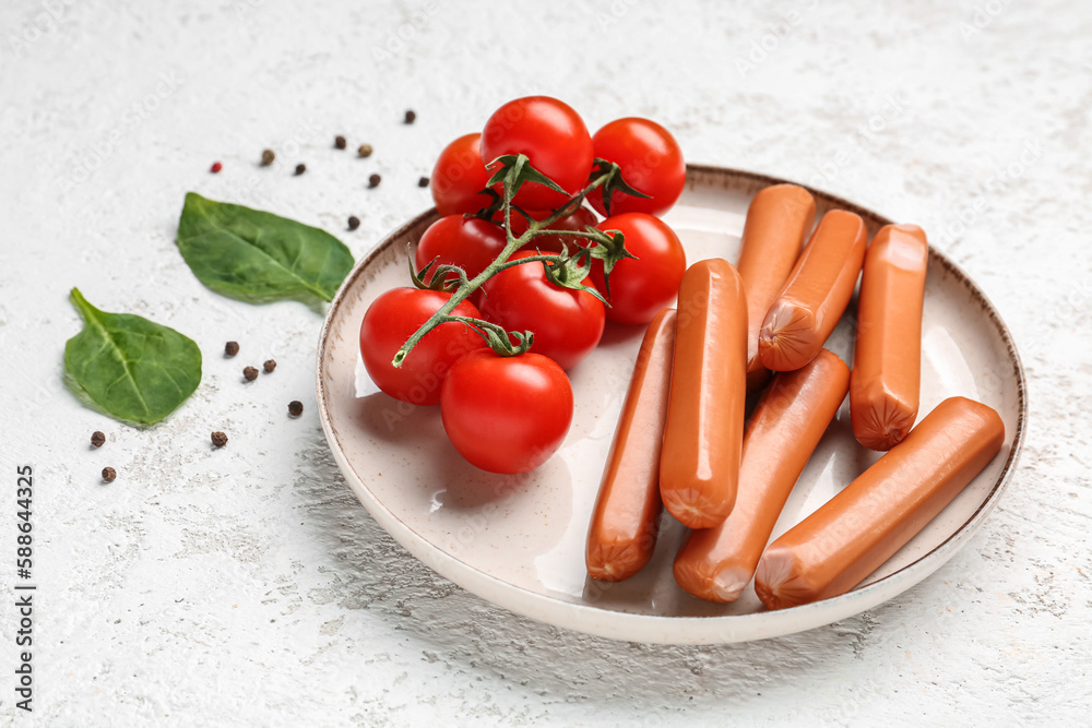 Plate with tasty sausages and tomatoes on light background