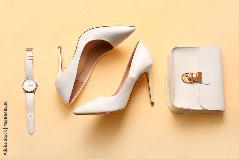 Stylish high heeled shoes and accessories on yellow background