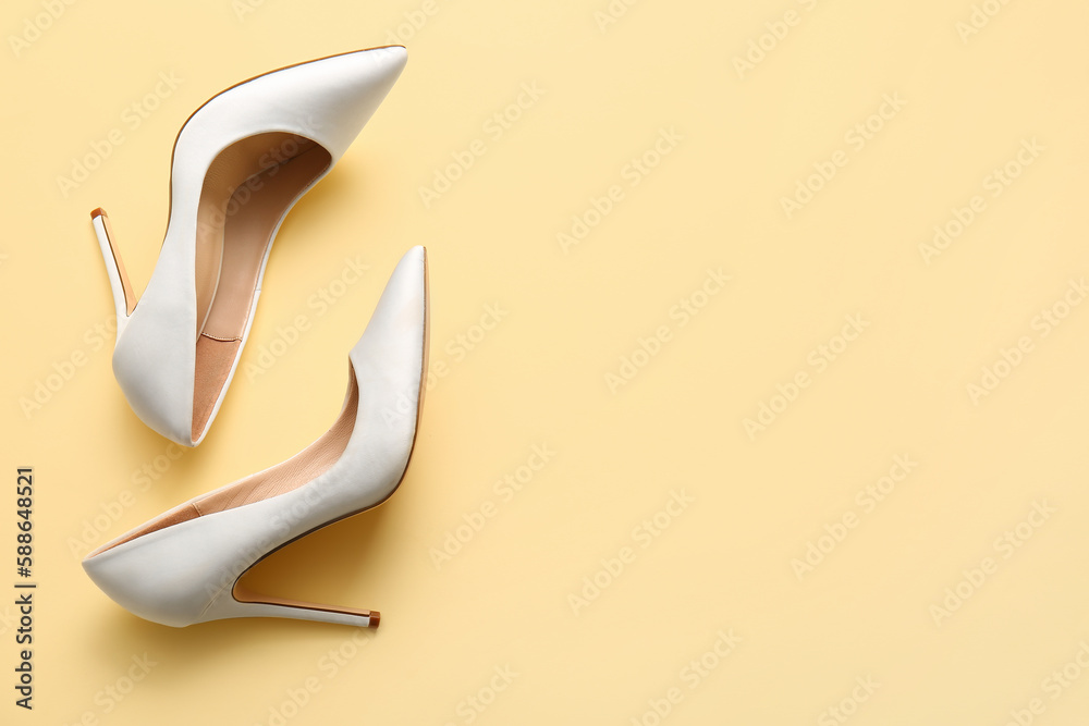 Pair of high heeled shoes on yellow background