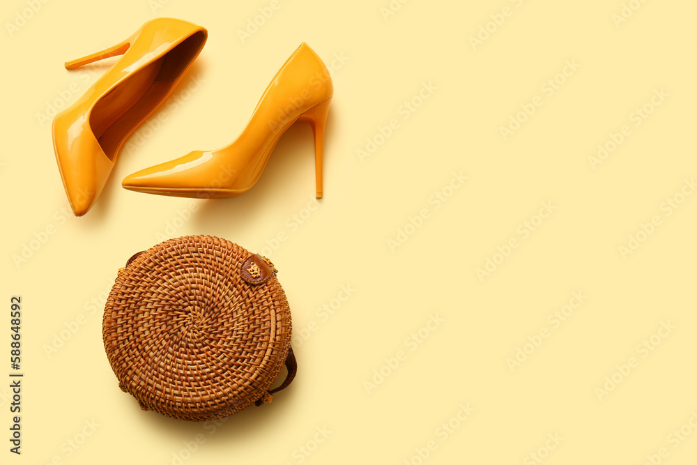 Stylish high heeled shoes and bag on yellow background