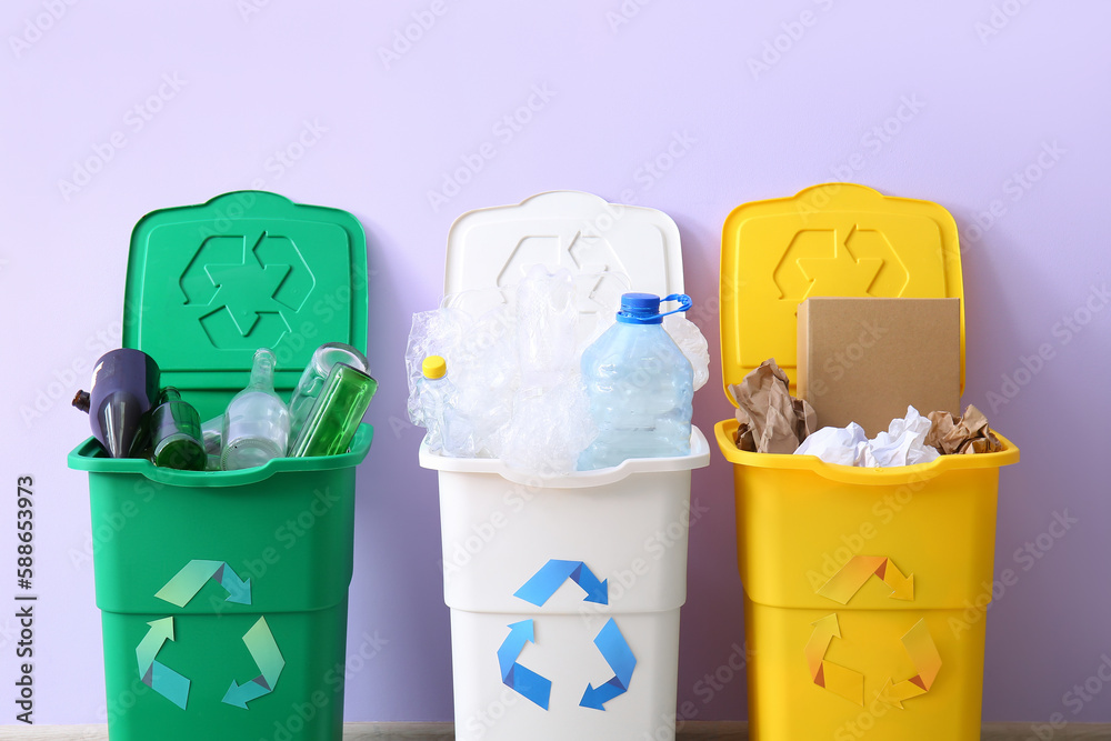 Containers with different types of garbage on lilac background. Recycling concept