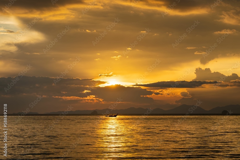 Calm waters of the sea with mountains and the golden sunset in the background in Thailand