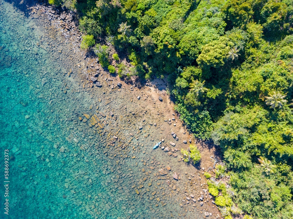 Top view of a small kayak on the rocky shore of the Koh Rat, Thailand with green trees