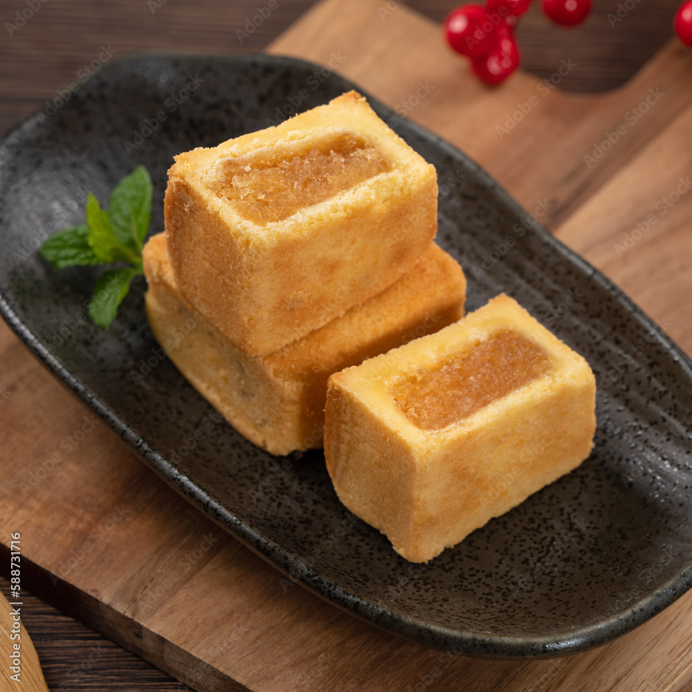 Delicious pineapple cake pastry in a plate on wooden table background with tea.